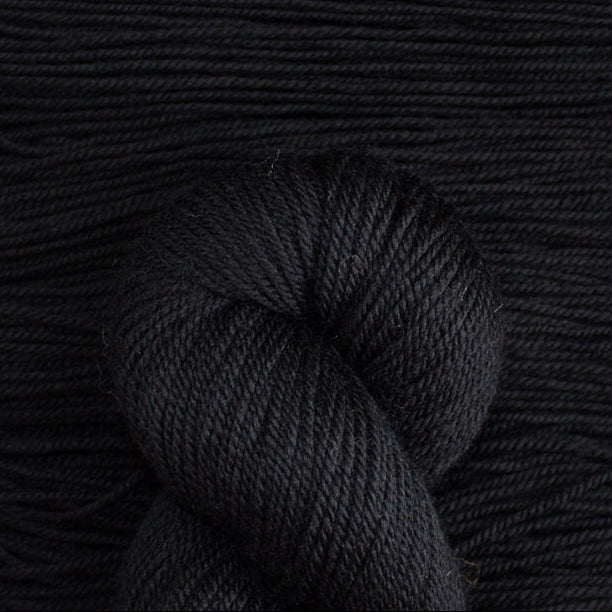 Close-up of black yarn with a skein on a textured black background