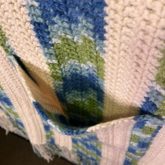 Close-up of a textured fabric with blue and green patterns on a smartphone screen.