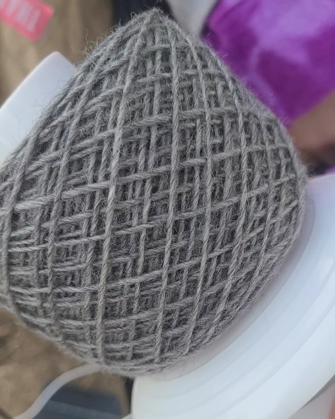 Textured gray yarn wound on a spinner.