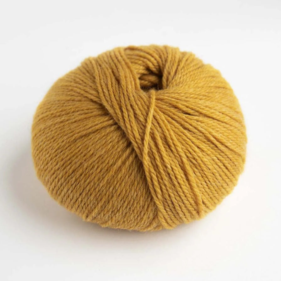 Ball of mustard yellow yarn on a white background