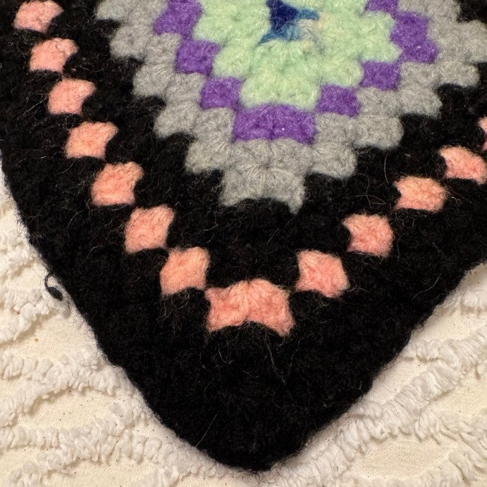 Close-up of a crocheted blanket with a diamond pattern on a textured surface.
