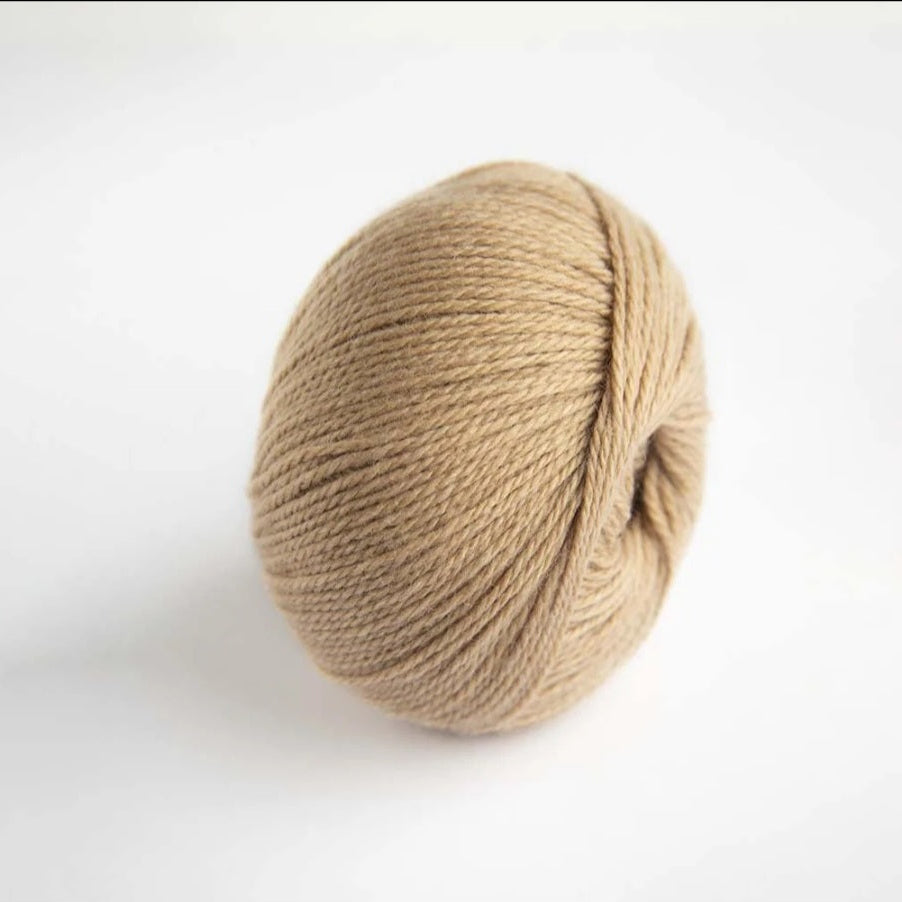 Ball of beige yarn on a white background