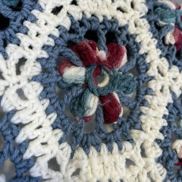 Close-up of a crocheted blanket with a floral pattern on a smartphone screen.