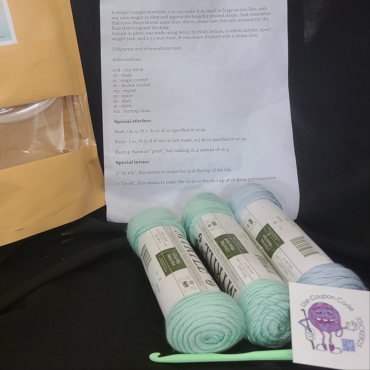 Yarn, an envelope, and a paper with text on a dark surface