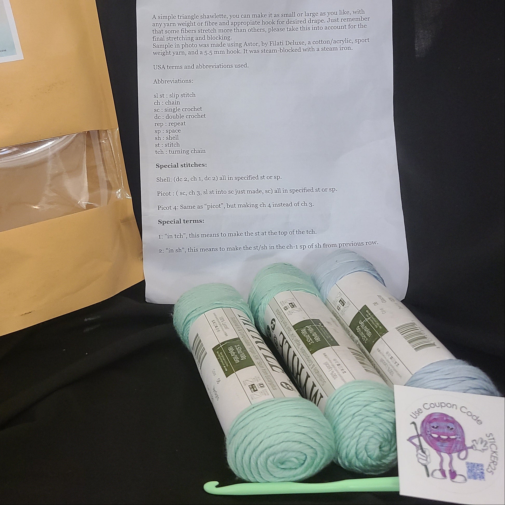 Yarn, an envelope, and a paper with text on a dark surface