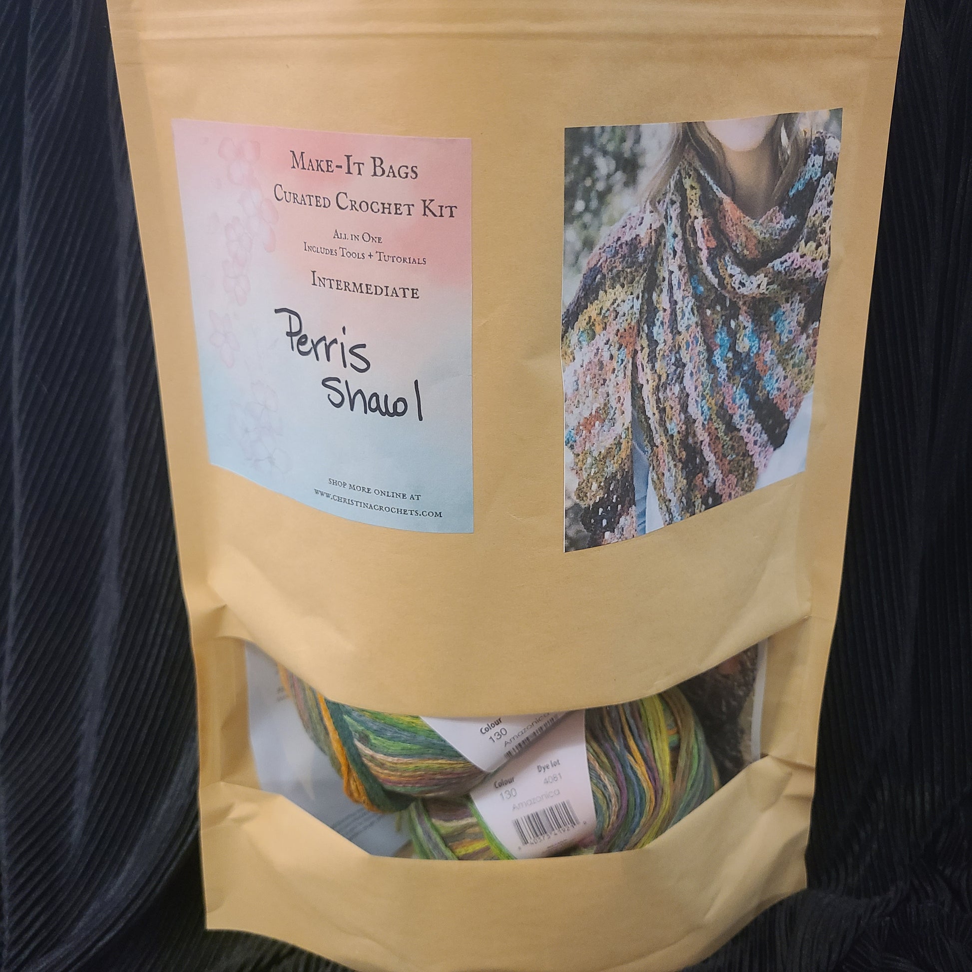 Open craft crochet kit packaging with colorful yarn and a label on a dark background