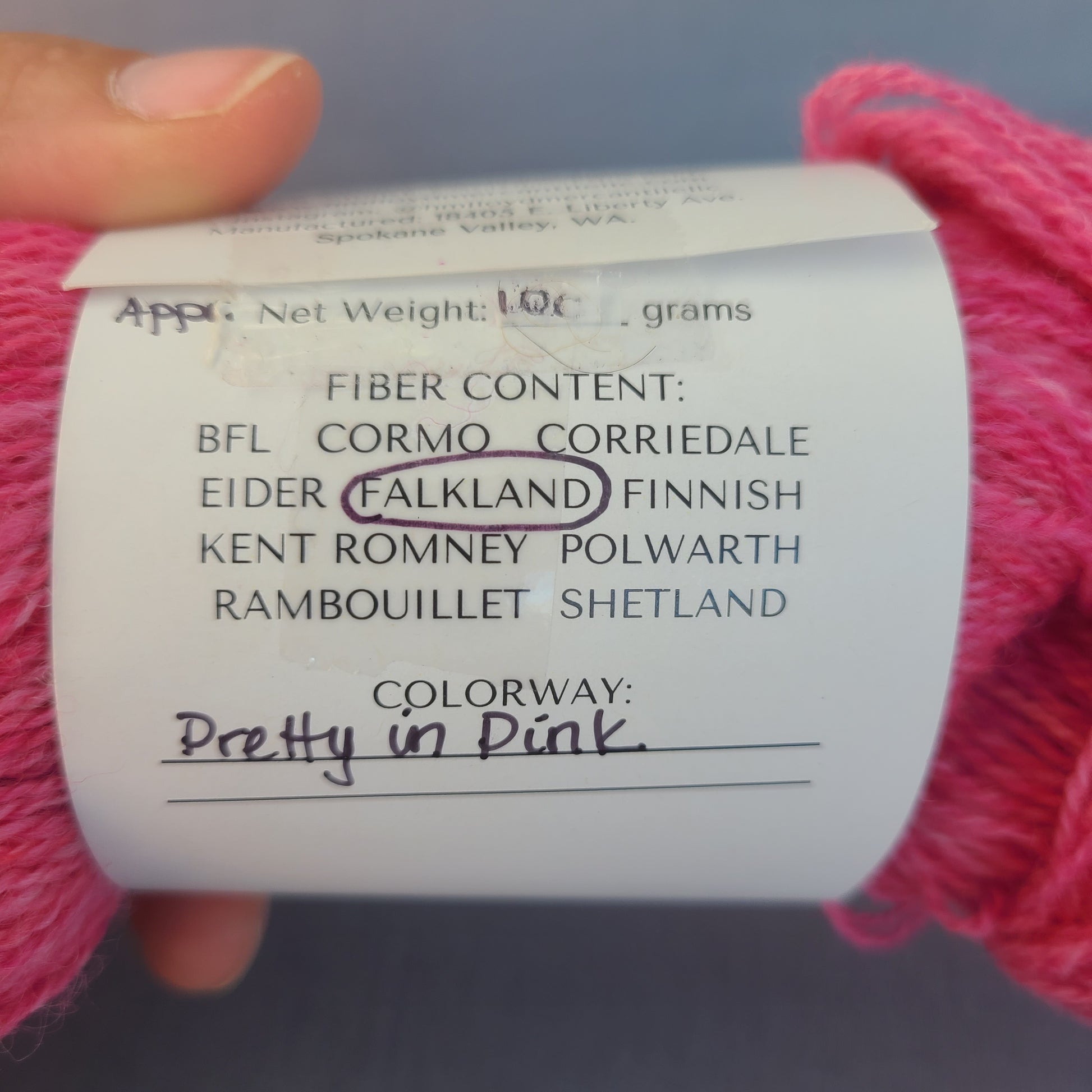 Yarn label with pink yarn on a gray background