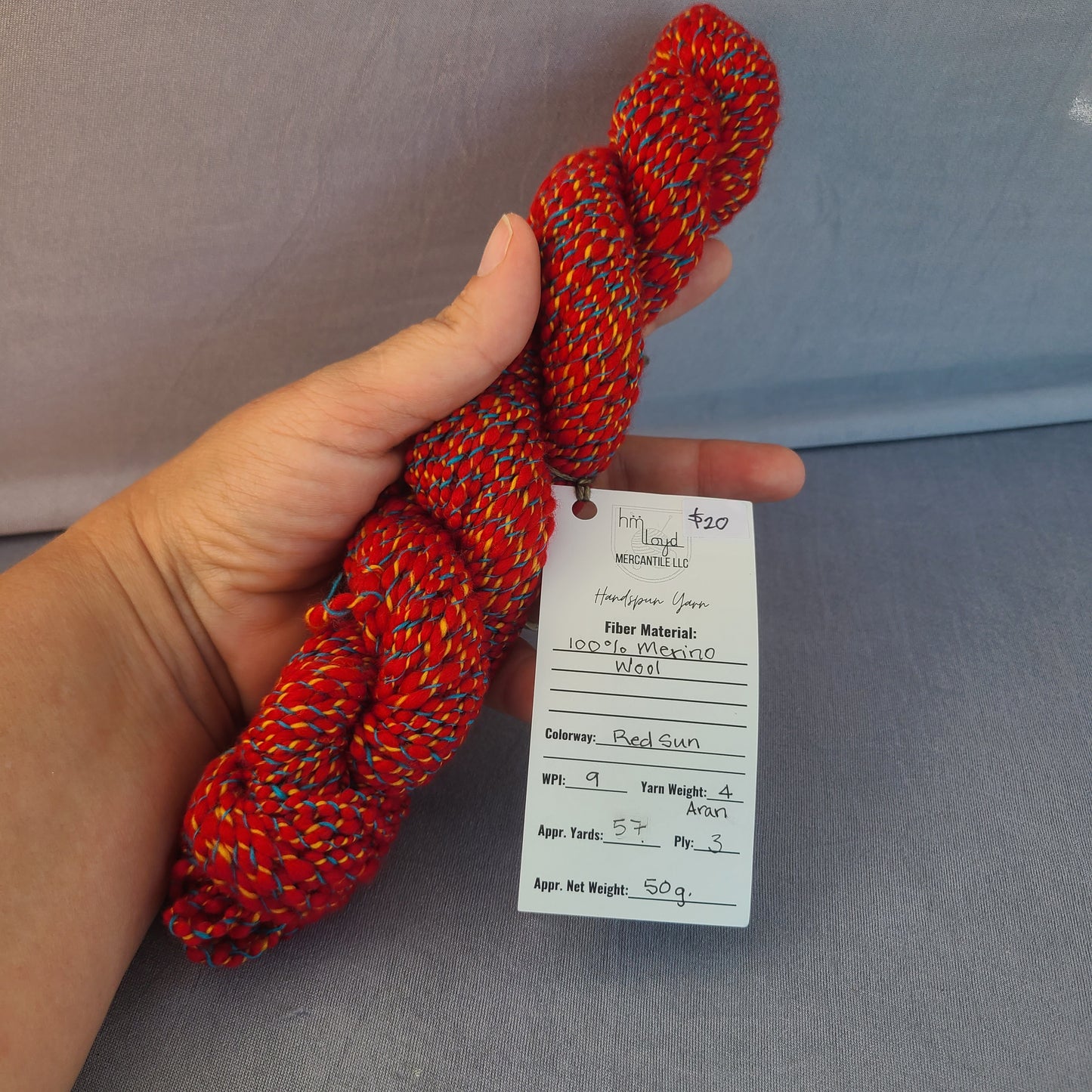 Hand holding a red rope with a label against a gray background