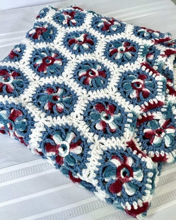 Crocheted blanket with blue, red, and white pattern on a white surface