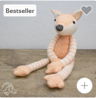 Stuffed fox toy with a heart icon and 'Bestseller' label on a wooden surface.