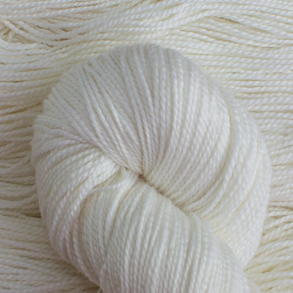 Close-up of a ball of white yarn with more yarn strands in the background.