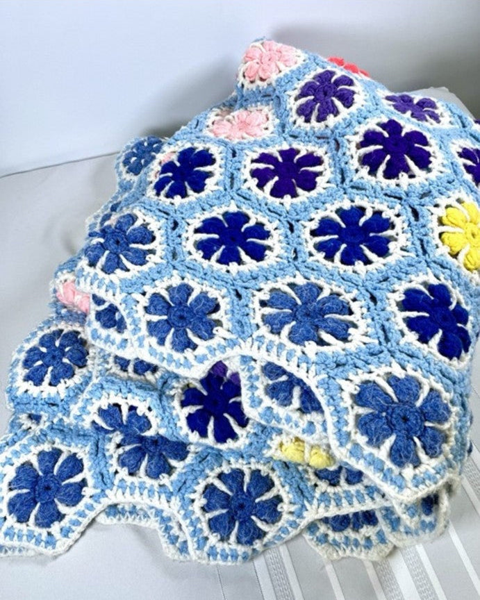 Crocheted blanket with blue and white pattern on a white surface