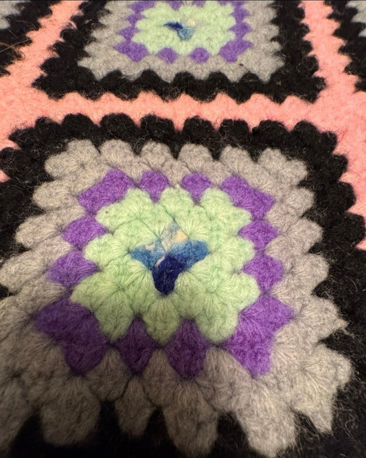 Close-up of a crocheted blanket with a colorful pattern, displayed on a smartphone screen.