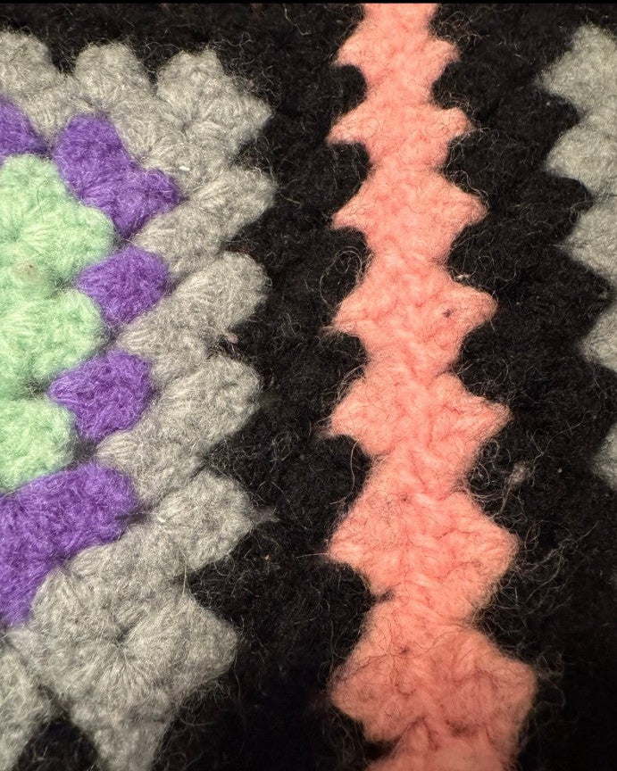 Close-up of a crocheted blanket with colorful patterns.