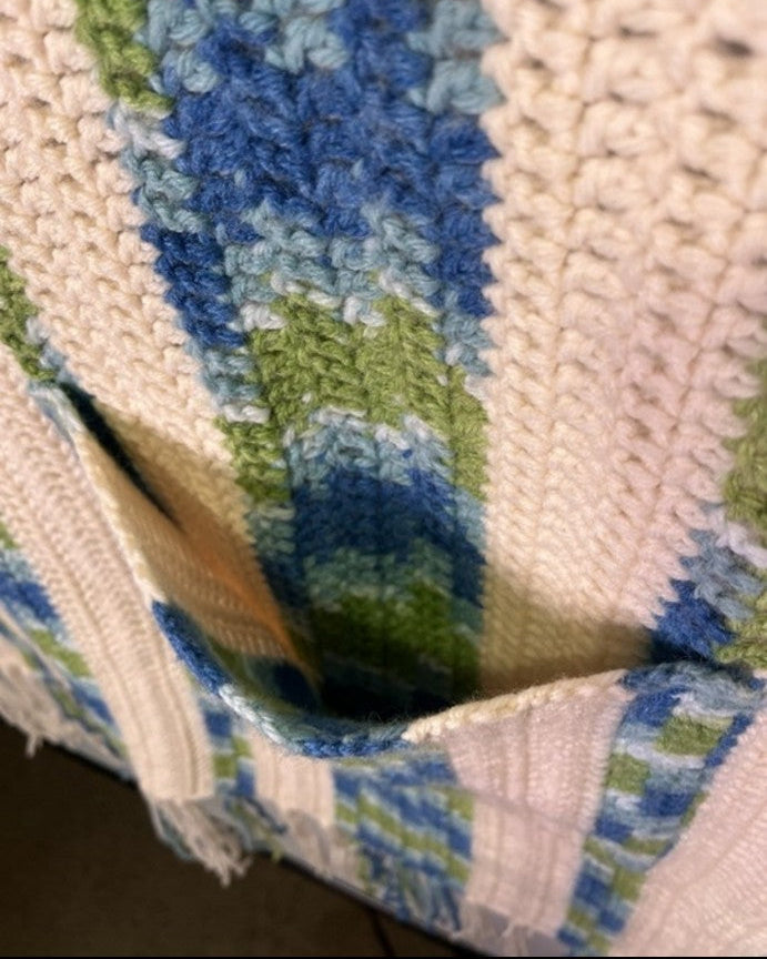 Close-up of a textured fabric with blue and green patterns on a smartphone screen.