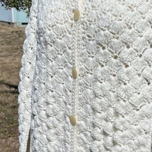 White textured coat on a mannequin outdoors with trees and grass in the background