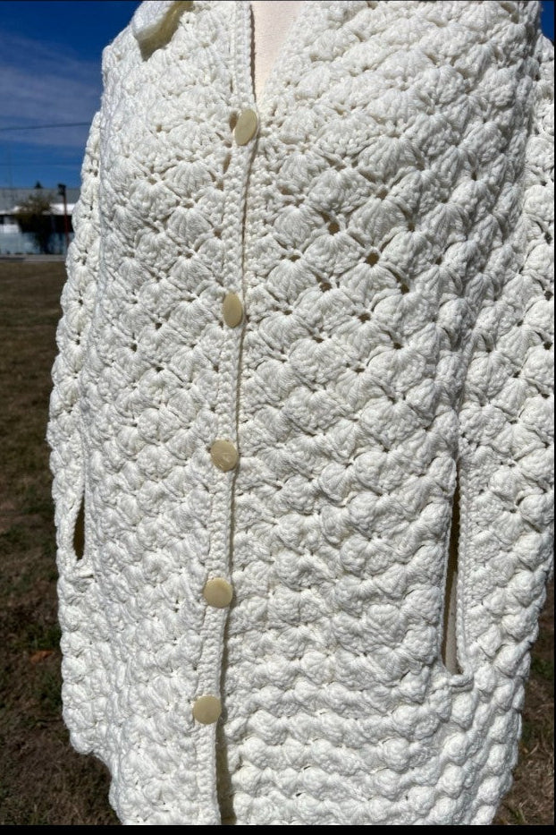 Close-up of a textured white garment with buttons, outdoors.