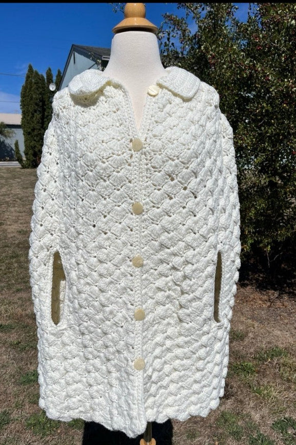 White textured coat on a mannequin outdoors with trees and grass in the background