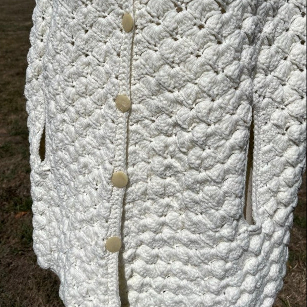 Close-up of a textured white garment with buttons, outdoors.