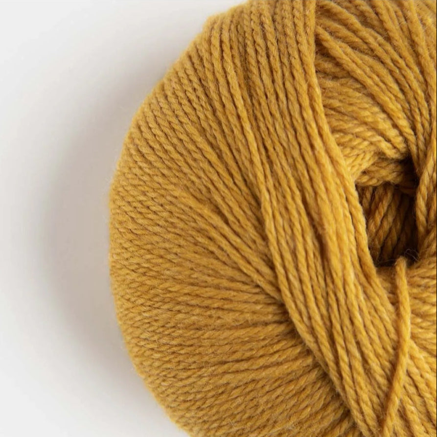 Ball of mustard yellow yarn on a white background