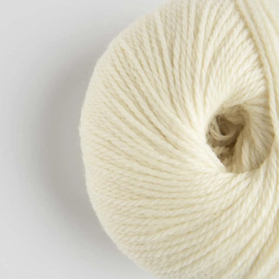 Close-up of a ball of cream-colored yarn on a light gray background