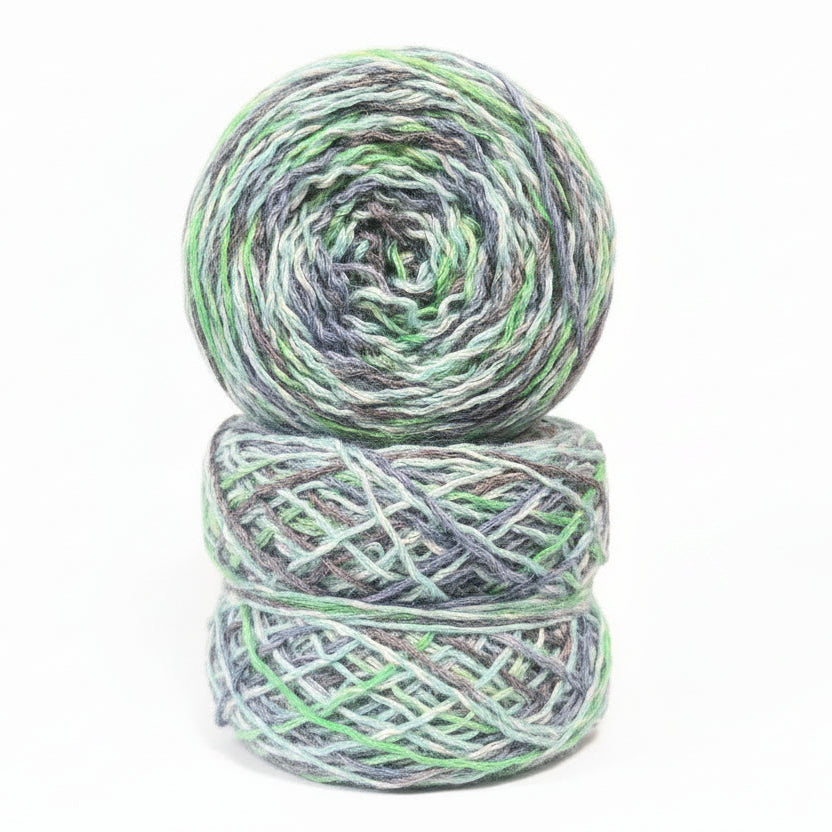 Two skeins of yarn with green and gray pattern on a dark textured background