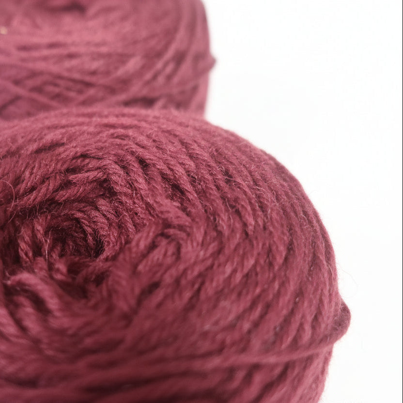 Close-up of a ball of dark red yarn on a dark background