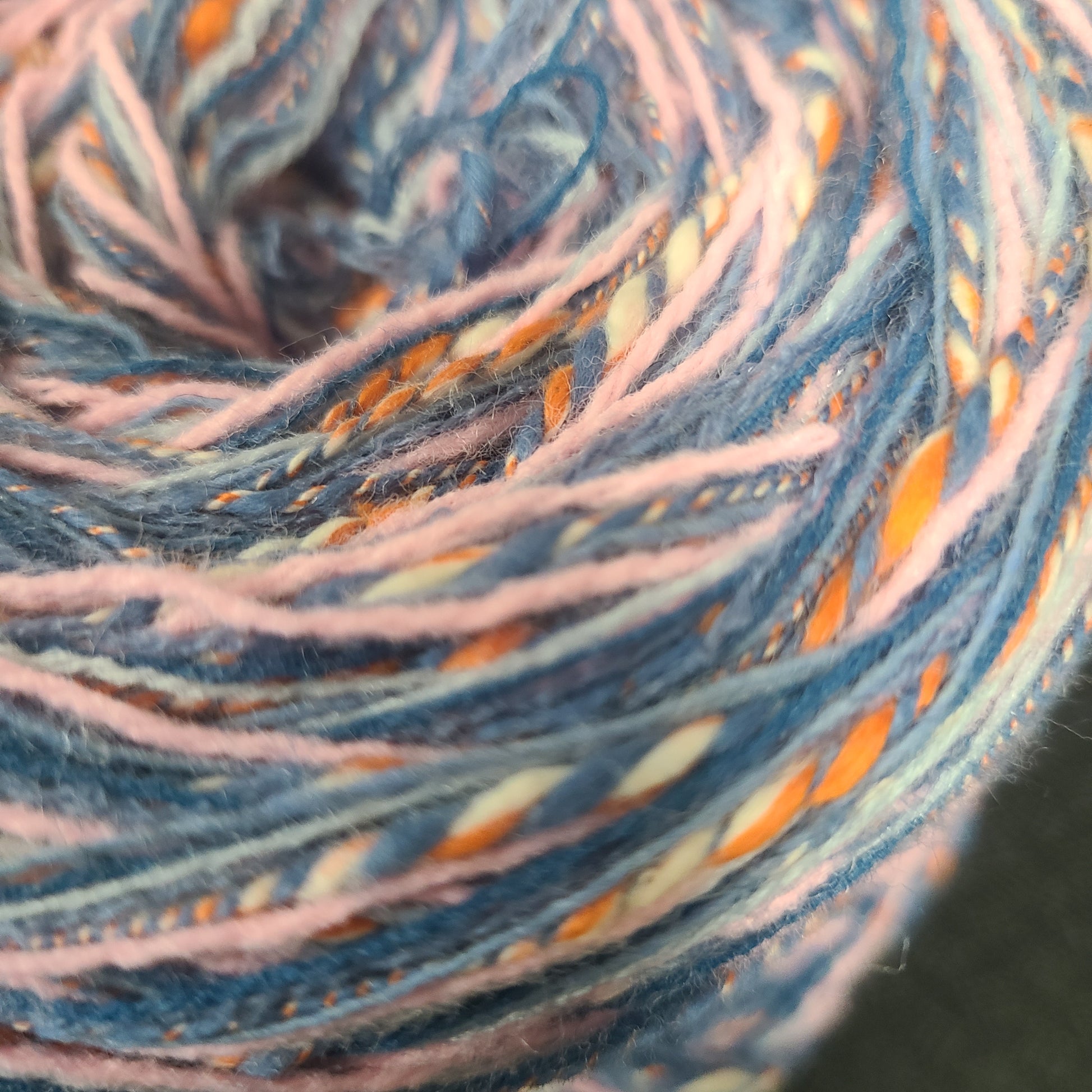 Close-up of a ball of multicolored yarn with blue, orange, and pink hues.