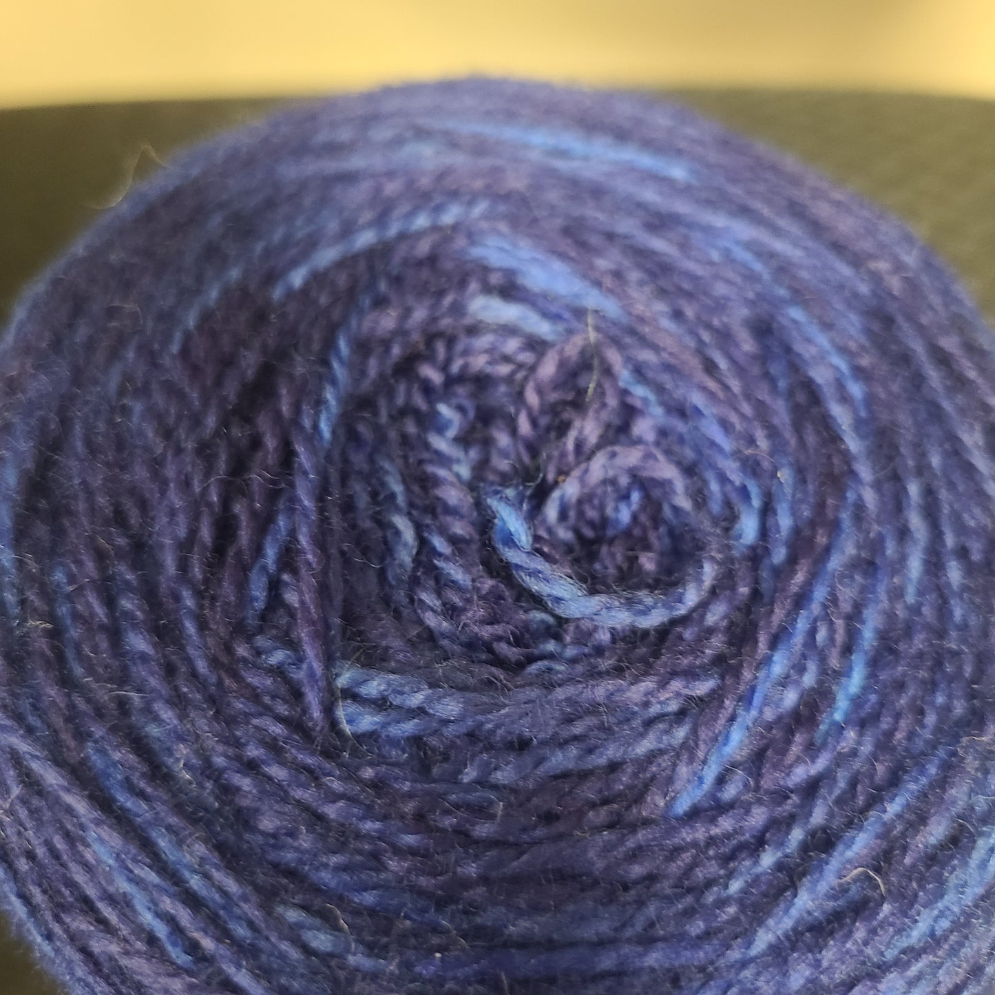 Close-up of a ball of dark blue yarn on a gold background