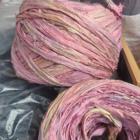 Two skeins of pink and purple yarn on a black surface