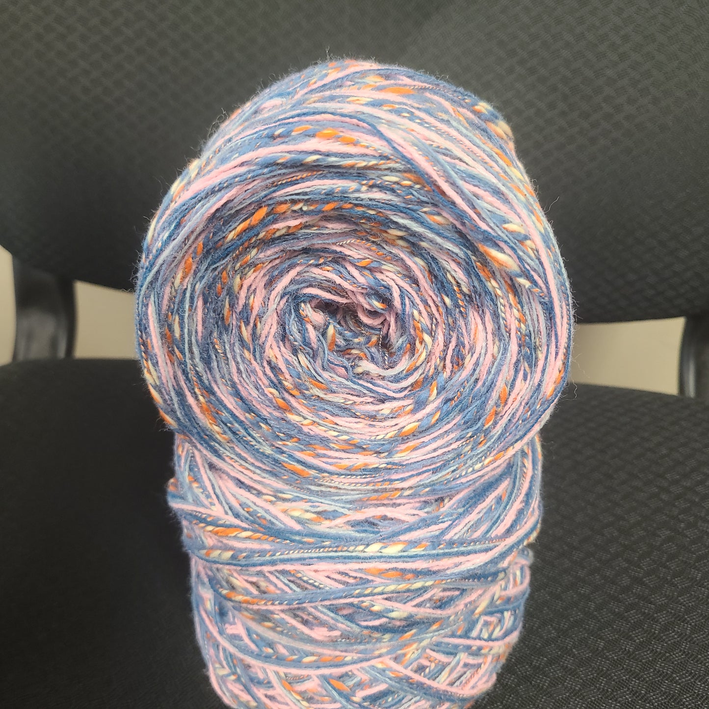 Multicolored yarn roll on a chair with a blurred background