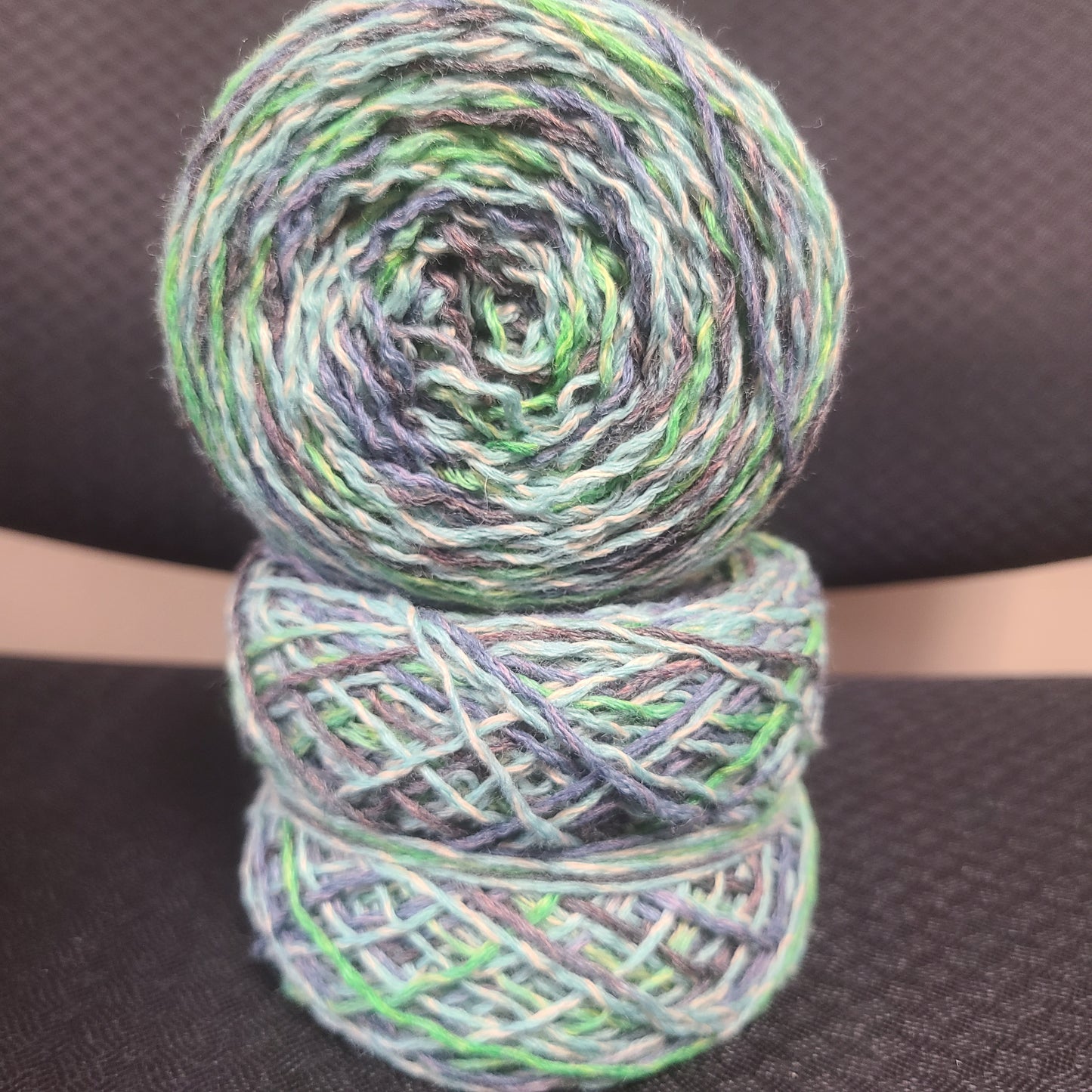 Two skeins of multicolored yarn on a dark textured background