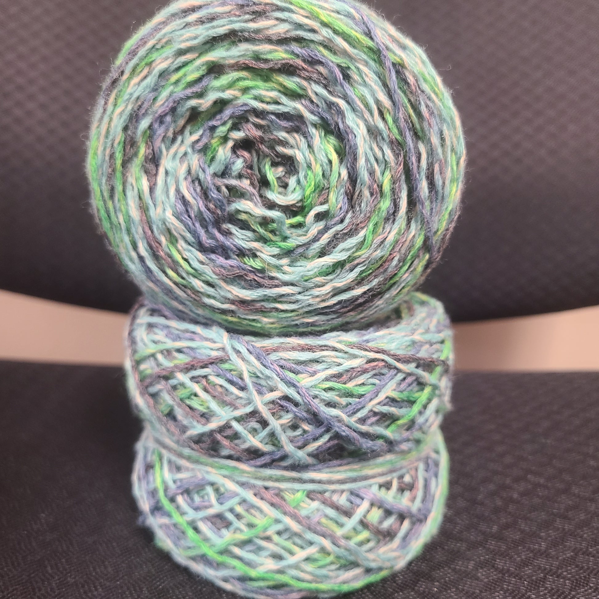 Two skeins of multicolored yarn on a dark textured background